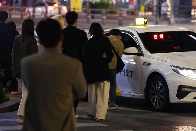 지난 18일 자정을 넘긴 시간 서울 강남역 인근에서 시민들이 빈 택시를 향해 모여들고 있다. /연합뉴스