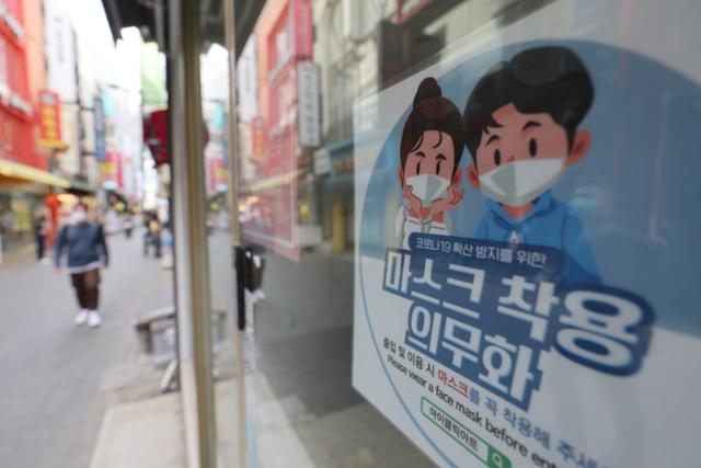 27일 오후 서울 중구 명동 거리의 한 매장에 마스크 의무 착용을 알리는 안내문이 붙어 있다. 연합뉴스