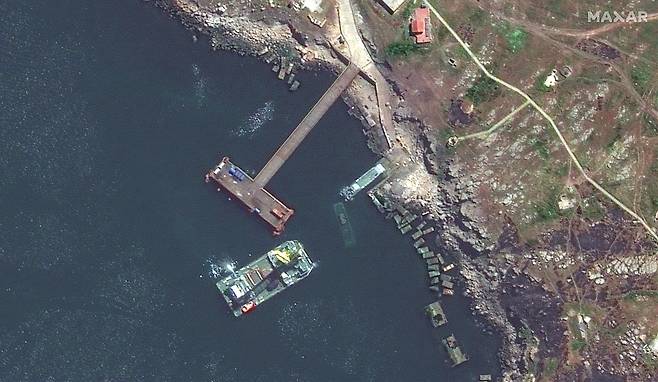 즈미니섬 인근에 중장비를 실은 러시아 바지선 옆으로 물 속에 침몰한 선박이 보인다.
