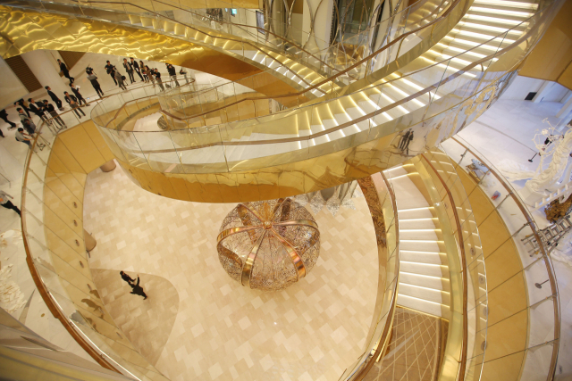 롯데 에비뉴엘 월드타워점의 2014년 오픈 당시 ‘여왕의 대관식’ 콘셉트의 인테리어로 주목받은 지하 1층 거대 왕관과 지상 1~2층을 잇는 샤롯데 계단. 연합뉴스