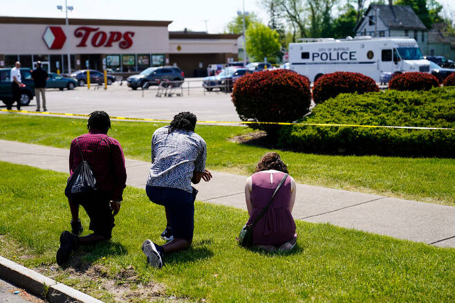 총기 난사 사건으로 전날 10명이 숨진 미국 뉴욕주 버팔로의 탑스 슈퍼마켓 들머리에서 15일(현지시각) 시민들이 무릎 꿇은 채 기도하고 있다. 버펄로/AP 연합뉴스