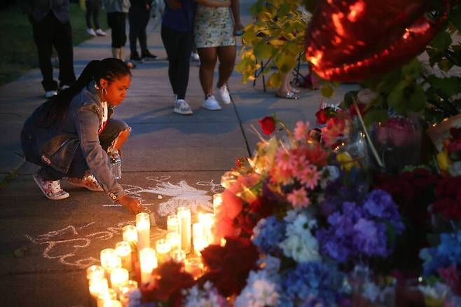15일 미국 뉴욕주 버팔로의 총기 난사 사건 현장 근처에서 한 시민이 분필로 추모 메시지를 쓰고 있다. 버팔로/AFP 연합뉴스