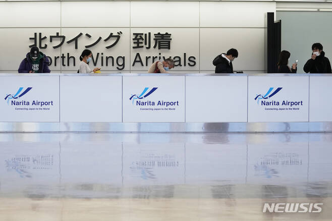 [나리타=AP/뉴시스]지난해 12월 2일 일본 나리타 국제공항의 국제선 도착 게이트에서 마스크를 착용한 승객들이 줄을 서고 있다. 2022.05.11