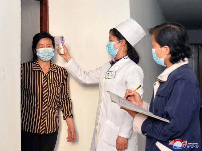 A medical worker checks a resident’s temperature using a non-contact thermometer in this photo released by the Korean Central News Agency on Tuesday. (Yonhap)