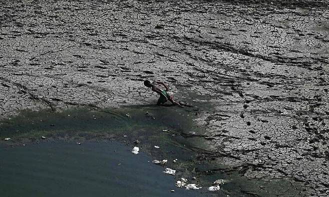 인도 소년이 폭염으로 바닥이 드러난 수도 뉴델리 자무나강을 힘겹게 걸어가고 있다. AFP연합뉴스
