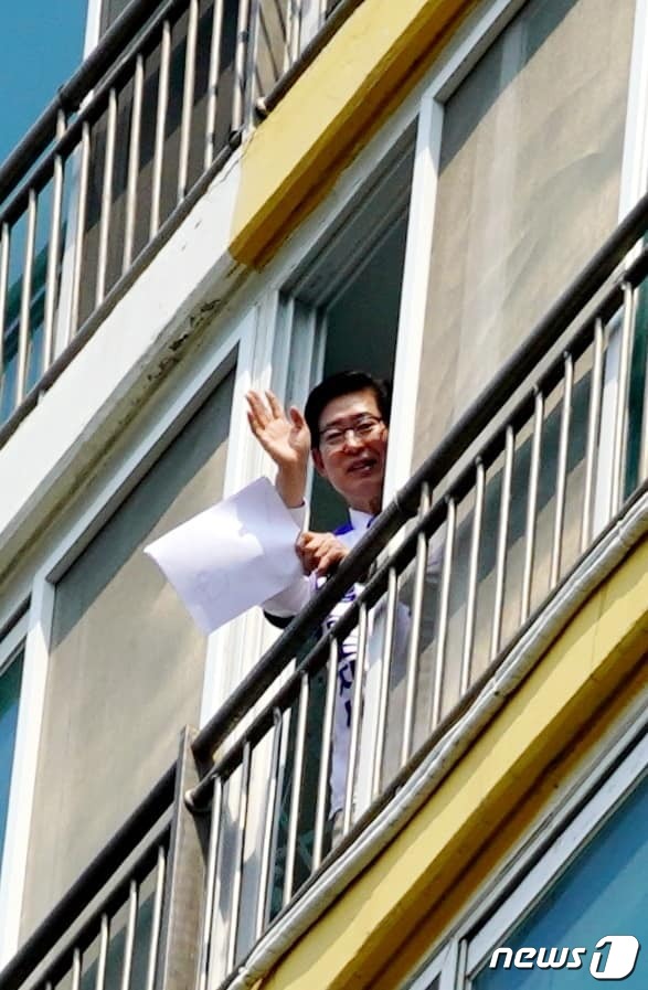 자가격리 중인 양승조 충남지사 후보가 22일 자택을 방문한 지지자들을 향해 손을 흔들고 있다.(양승조 후보 SNS 캡처)© 뉴스1