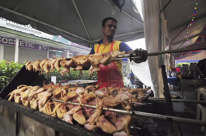 [쿠알라룸푸르=AP/뉴시스] 지난 2017년 6월7일(현지시간) 말레이시아 쿠알라룸푸르에서 라마단 기간 중 한 남성이 바자회에서 닭고기를 굽고 있다.  *재판매 및 DB 금지