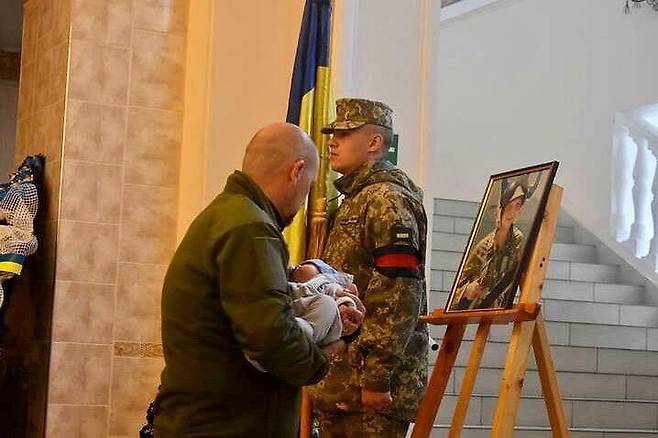 [서울=뉴시스] 지난 18일(현지시간) 우크라이나 서부 빈니차에서 거행된 장례식에 세르히 파르호멘코 대위의 2개월 된 아들이 참석한 모습. 파르호멘코 대위는 지난 14일 우크라이나 동부 자포리자 지역에서 전투 중 사망했다. (사진=우크라이나 군사정보 홈페이지 갈무리) 2022.05.24. *재판매 및 DB 금지