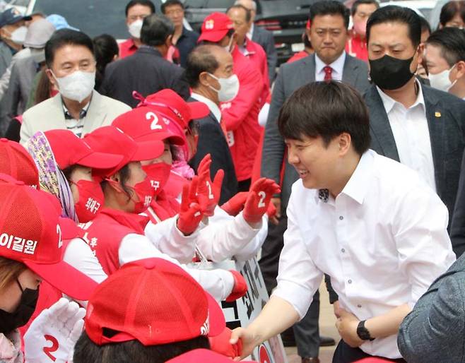 이준석(오른쪽) 국민의힘 대표가 25일 충남 예산시장에서 선거운동원과 악수하고 있다. 연합뉴스
