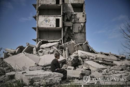 러시아의 포격으로 파괴된 크라마토르스크 시의 건물 앞에 앉아 있는 소년  [AFP 연합뉴스 자료사진. 재판매 및 DB 금지]