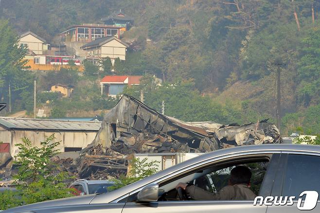 29일 오전 경북 울진군 근남면에서 발생한 산불로 산림과 인접한 곳에 있던 자동차 정비소가 젯더미로 변했다.. 도로를 지나던 시민이 불에 탄 자동차 정비소를 지켜보고 있다.2022.5.29/© 뉴스1