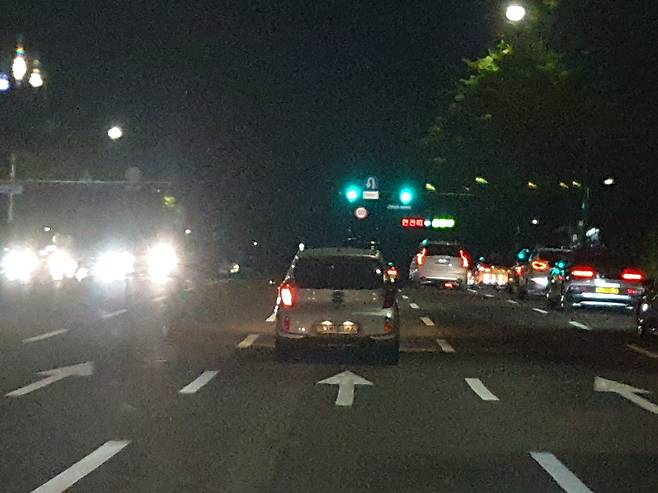 오른쪽 미등이 꺼진 승용차가 밤 시간 도심을 달리고 있다.