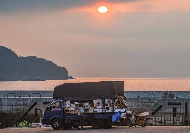 "오늘도 웃고는 있지만 오이가 너무 안 팔려 걱정이야. 싸길래 너무 많이 샀어. 날씨가 안 좋을 때가 제일 큰 걱정이지. 배가 안 뜨면 준비해둔 채소들 다 버려야 해"