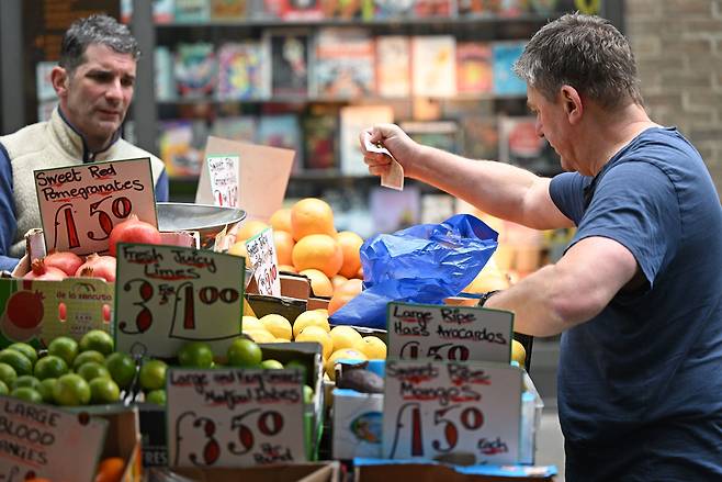 지난달 12일(현지 시각) 영국 런던의 한 청과물 가게에서 한 고객이 과일과 채소 대금으로 10파운드 지폐를 건네고 있다. /연합뉴스