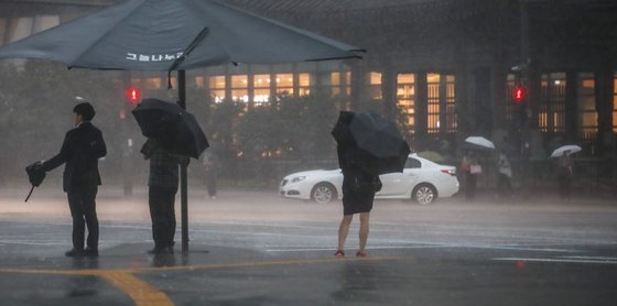 국적으로 장맛비가 내리고 있는 23일 오후 서울 종로구 광화문광장 인근에서 쏟아지는 폭우에 시민들이 우산을 쓴 채 이동하고 있다. 뉴시스