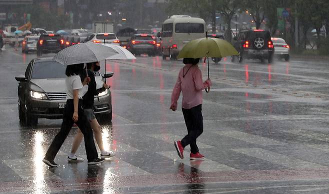 장맛비가 내리는 23일 오후 서울 시청 인근 횡단보도에서 우산을 쓴 시민들이 발걸음을 재촉하고 있다. 뉴스1