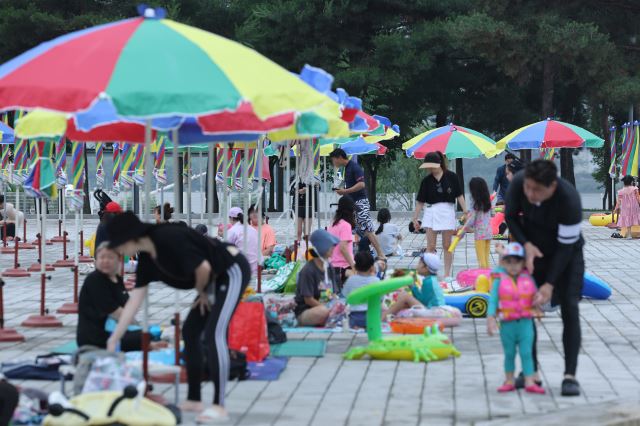 서울 광진구 뚝섬 한강공원 수영장을 찾은 이용객들이 24일 파라솔 밑에서 쉬고 있다. 연합뉴스
