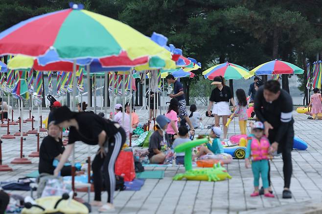 24일 오후 3년 만에 재개장한 서울 광진구 뚝섬 한강공원 수영장을 찾은 이용객들이 파라솔 아래서 쉬고 있다. [연합]