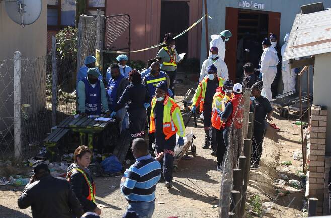 남아프리카공화국 경찰들이 26일(현지시간) 남아공 이스트런던의 타운십에 있는 한 술집에서 시신을 옮기고 있다. [AFP=연합뉴스]