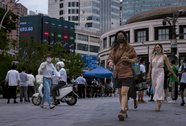 상하이 시민들이 23일 최신 경제 지표와 증권거래소 수치를 보여주는 전광판이 설치된 도심 번화가를 걸어가고 있다. EPA연합