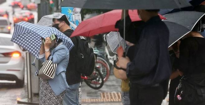 강풍을 동반한 소나기가 내린 28일 오후 서울 마포구 지하철 홍대입구역 인근 건널목 앞에 시민들이 우산을 들고 서 있다. 연합뉴스