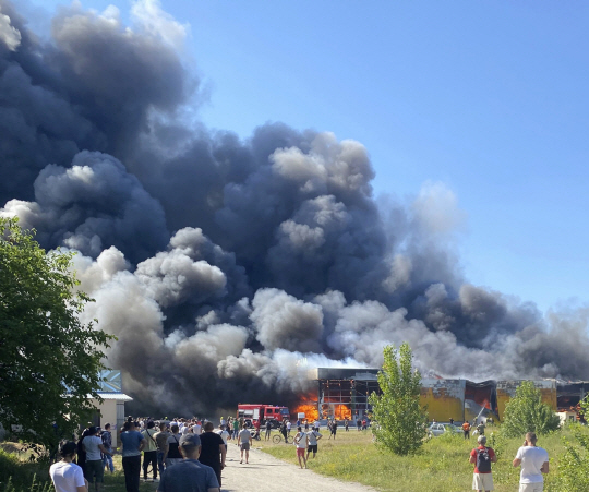 27일(현지시간) 우크라이나 폴타바 주 크레멘추크 시의 쇼핑몰이 러시아 미사일 공격을 받은 후 불타고 있는 모습을 시민들이 지켜보고 있다. AP뉴시스