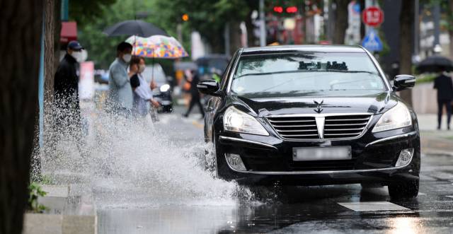 이번 주 내내 장맛비가 내릴 것으로 예보된 27일 오후 서울 종로구 광화문 새문안로에서 차량이 물보라를 일으키고 있다. 연합뉴스
