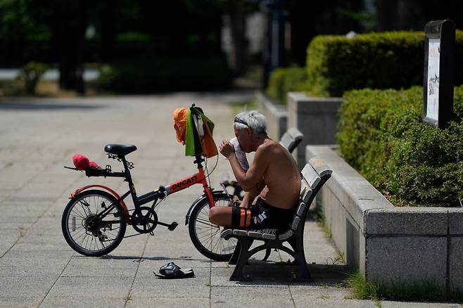 일본 도쿄의 한 공원에서 자전거 운전자가 폭염 속에 휴식을 취하며 얼굴의 땀을 닦아내고 있다. /연합뉴스