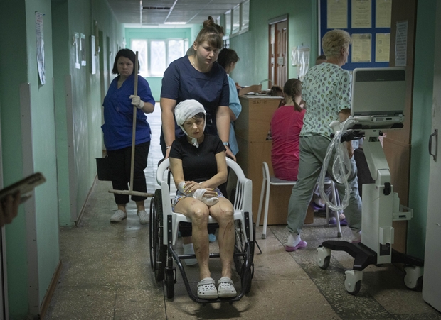 28일(현지시간) 우크라이나 폴타바주 크레멘추크시립병원에서 간호사가 쇼핑몰 생존자를 휠체어에 태워 가고 있다. AP 연합뉴스