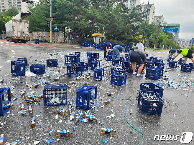 지난 29일 춘천시 퇴계동의 한 사거리에서 5톤 트럭에 실려있던 맥주병 2000여병이 바닥으로 떨어지는 사고가 발생, 길을 가던 시민들이 청소를 돕고 있다.(독자 제공)© 뉴스1