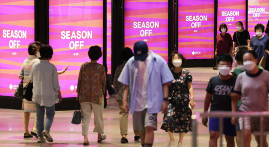 　 : 지난 24일 서울 시내 한 백화점 입구에 설치된 정기세일 홍보물 사이로 시민들이 걸어가고 있다. 연합뉴스
