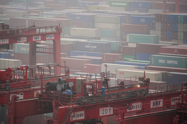 FILE PHOTO: Workers are seen on a crane above containers at the Yangshan Deep Water Port in Shanghai, China January 13, 2022. Picture taken January 13, 2022. REUTERS/Aly Song/File Photo