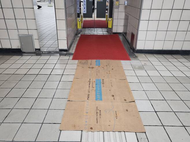 지난 30일 오후 7시쯤 서울시 영등포구 신길동에 있는 신길역 엘리베이터 앞 시각장애인 점자블록 위로 미끄럼 방지용 카펫과 종이 박스가 덮여 있는 모습/정재훤 기자