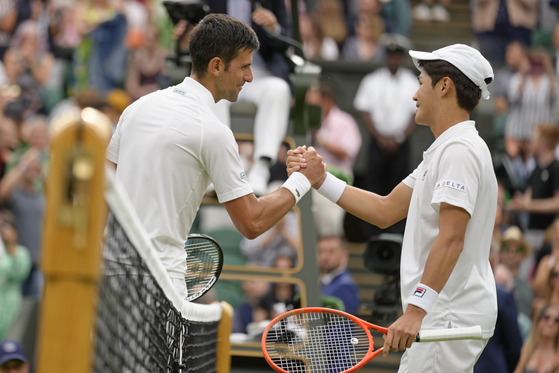 Serbia's Novak Djokovic greets Kwon Soon-woo, right, at the net after winning their men's first round singles match on day one of Wimbledon at the Centre Court of the All England Lawn Tennis and Croquet Club in London on Monday. [AP/YONHAP]