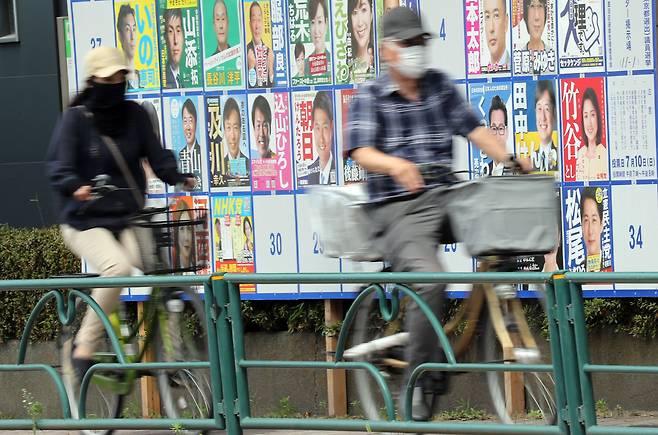 일본 참의원 선거 투표일인 10일 오후 도쿄도 스미다구에 설치된 후보자 안내판 앞으로 자전거를 탄 사람이 지나가고 있다. /연합뉴스
