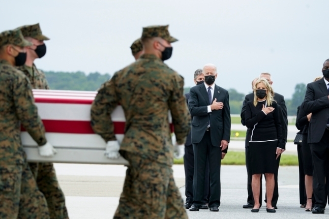 조 바이든 미국 대통령과 영부인 질 여사가 2021년 8월29일 델라웨어주 도버 공군기지에 도착한 아프가니스탄 테러 전사 군인 13명의 관이 운구되는 모습을 가슴에 손을 얹고 지켜보고 있다. AP연합뉴스