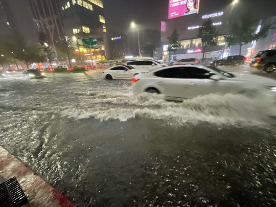 물살을 가르며... : 수도권 집중호우가 내린 8일 밤 서울 강남구 신사역 일대 도로가 물에 잠겨 차량들이 힘겹게 주행하고 있다. 연합뉴스
