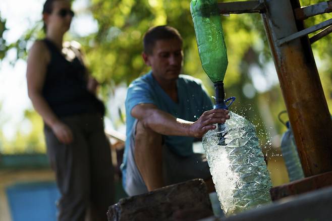 우크라이나 동부 슬로우얀스크의 주민이 공용 식수 시설에서 플라스틱 통에 물을 담고 있다. 슬로우얀스크/AP 연합뉴스