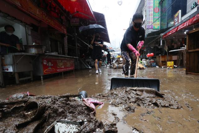 9일 폭우로 침수피해를 입은 서울 동작구 남성사계시장의 한 상인이 거리로 쏟아진 토사물을 쓸어 내고 있다. 연합뉴스