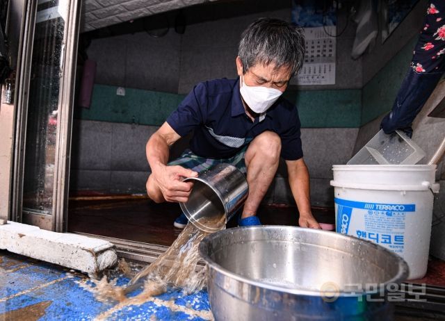 10일 서울 동작구 남성사계시장에서 한 상인이 창고로 사용하던 공간의 물을 빼내고 있다.