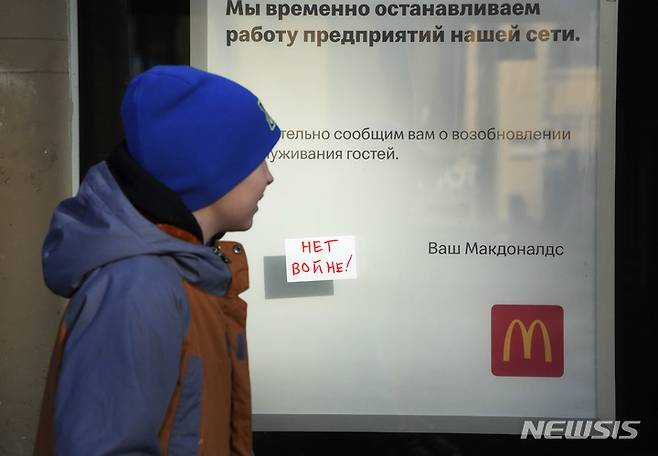 [상트페테르부르크=AP/뉴시스] 지난 3월15일(현지시간) 러시아 상트페테르부르크에서 한 소년이 폐점을 알리는 문구와 "전쟁 반대"라는 메모가 붙은 맥도날드 매장 앞을 지나고 있다. 2022.03.16.