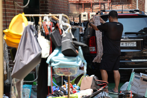 12일 오후 서울 관악구 신림동 일대에서 폭우로 피해를 입은 주민이 침수된 물품들을 햇빛에 말리고 있다.(사진=연합뉴스)