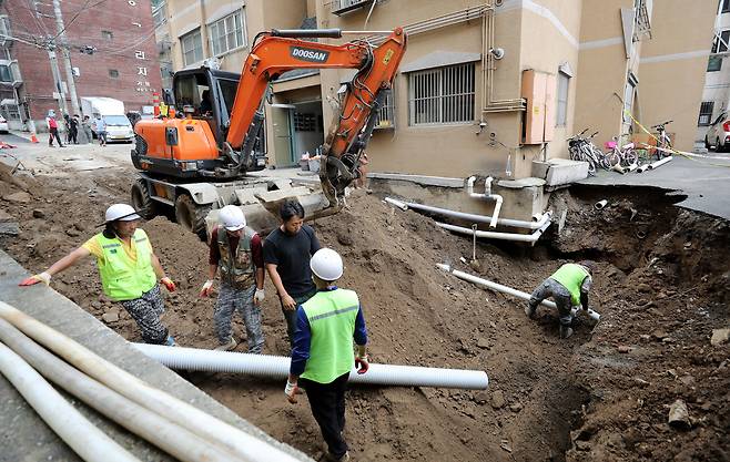 집중호우로 대형 싱크홀이 발생한 서울 양천구 신월동의 한 주택가에서 10일 오후 구청 관계자들이 복구 작업을 진행하고 있다./뉴스1