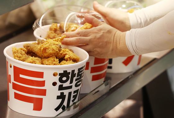 An employee displays fried chicken at Lotte Mart. The discount mart will sell a bucket of fried chicken for 8,800 won between Thursday and Aug. 17. [YONHAP]