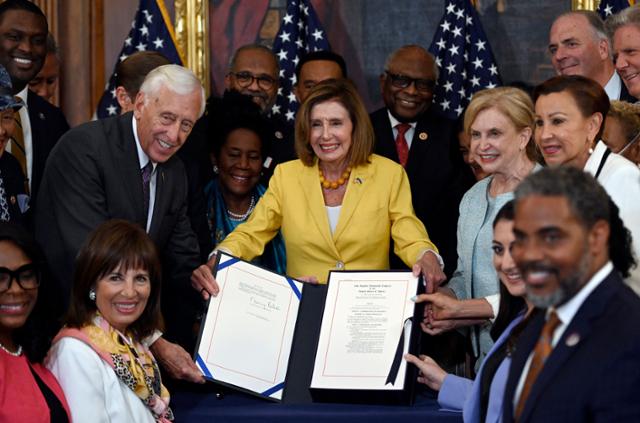 낸시 펠로시(가운데) 미국 하원의장이 12일 워싱턴 국회의사당에서 인플레감축법 통과를 서명한 뒤 의원들과 축하하고 있다. 워싱턴=AFP 연합뉴스