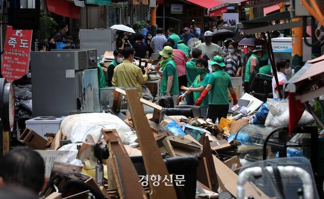 폭우로 인한 침수 피해를 입은 서울 동장구 남성사계시장에서 지난 10일 서울시새마을회원들과 환경미화원, 상인들이 복구 작업을 하고 있다. |김창길기자