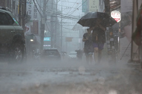 지난 8일 오후 서울 강동구 둔촌역 전통시장에서 시민들이 우산을 쓰고 이동하고 있다. 사진=뉴시스