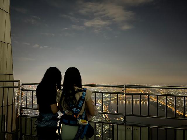 12일 서울 송파구 롯데월드타워 123층 옥상에서 진행된 비박 체험 행사 참가자들이 서울 밤 풍경을 구경하고 있다. 소진영 인턴기자