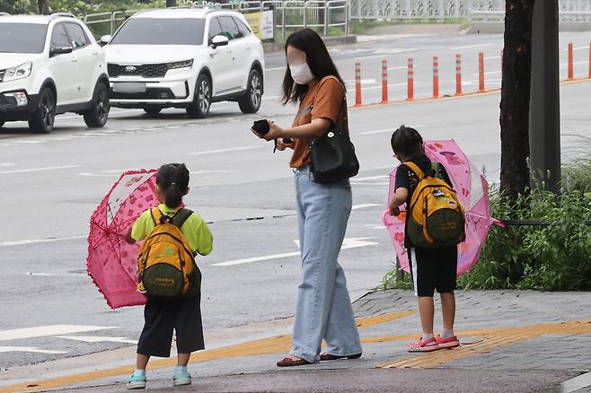 11일 오전 출근 시간 한 시민과 어린이들이 서울 마포구 마포구청역 인근에서 약하게 내리는 비에 우산을 내리고 있다. [연합]