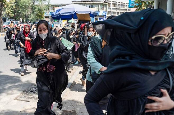 13일 아프가니스탄 수도 카불에서 탈레반 대원들이 공중에 총을 발사하자, 탈레반 정권에 항의하는 시위를 벌이던 여성들이 도망가고 있다. AFP 연합뉴스